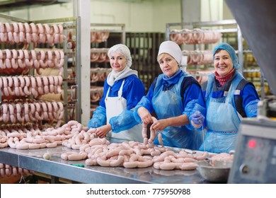 Butchers processing sausages at meat factory. - Powered by Shutterstock