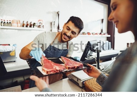 Butcher's shop seller helps to choose product to woman customer