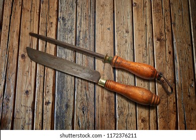 Butchery Knife And Sharpening Stick On Wooden Textured Table From Above