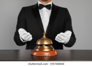 Butler at desk with service bell on grey background, closeup