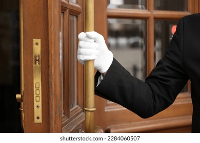 Butler in elegant suit and white gloves opening hotel door, closeup - Powered by Shutterstock