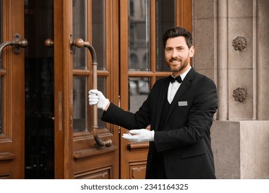 Butler in elegant suit and white gloves opening wooden hotel door - Powered by Shutterstock