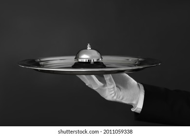 Butler holding metal tray with service bell on black background, closeup
