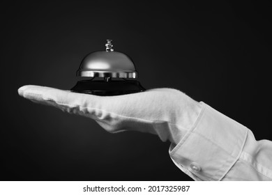 Butler holding service bell on black background, closeup