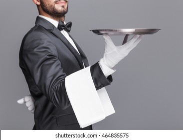 Butler holding a silver tray on gray background