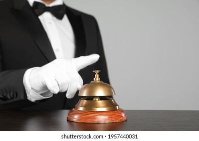 Butler ringing service bell at table, closeup. Space for text