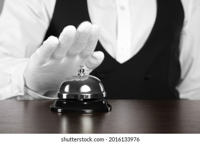 Butler ringing service bell at table, closeup