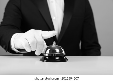 Butler ringing service bell at white table, closeup