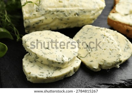 Butter with herbs and bread on table, closeup
