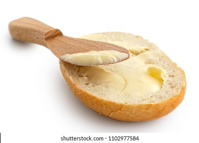 Butter Spread On A Half Of Crusty Bread Roll With A Wooden Knife Isolated On White.