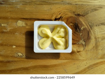 Butter in a white plastic container on the top of wooden table. A single serve pack - Shutterstock ID 2258599649