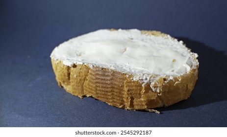 buttered single piece of a bread on a black background, on which he leave a shadow of himself - Powered by Shutterstock