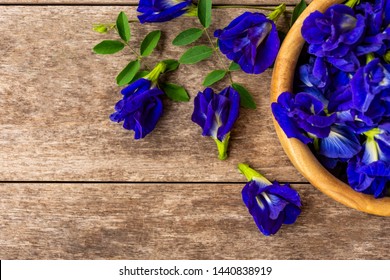 Butterfly pea or blue pea ,bluebellvine,cordofan pea(clitoria ternatea)in wooden bowl isolated on wood background. Space for text and content. Top view.