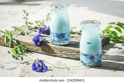 Butterfly Pea Blue Tea Latte With Blue Jelly Served In A Jar. Topping With White Milk Froth And Fresh Butterfly Pea Petals