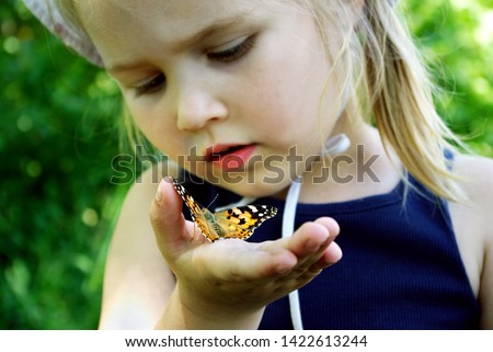 Butterfly sitting on the hand of a child. Child with a butterfly. Butterfly painted lady on the hand of a little girl. Selective focus.