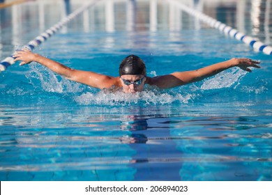 Butterfly swimmer in cap and glasses in the pool