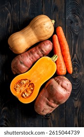 Butternut squash carrot sweet potato isolated on black wood background