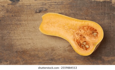 butternut squash cut in half revealing vibrant orange flesh and seeds on cutting board background, taken from above with copy space - Powered by Shutterstock