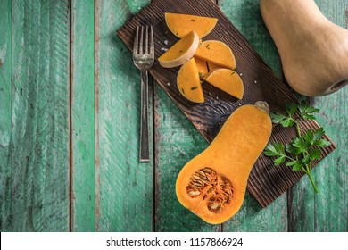 butternut squash over old wood background, Pumpkin pieces, harvest, fall. Dark brown background. Cooking in autumn. Healthy food.