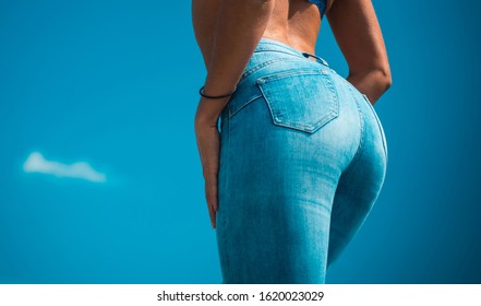 Buttocks in denim blue jeans close-up. Fashion and seduction concept. Fit female butt in blue jeans on sky background. Pretty sexy woman model with amazing slim body. Hot buttocks and hands.