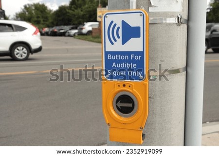 button for audible signal only crosswalk button with illustration of speaker making noise with road behind with vehicle stopped, blue while yellow and black