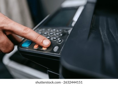 Button press on a multifunction printer for scanning documents in an office setting during daytime