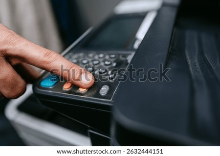Button press on a multifunction printer for scanning documents in an office setting during daytime