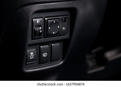 The button for the stability control system, side mirrors adjust and headlight washer on black panel of car near the steering wheel to overcome off-road, impassable roads drive safely in snow or rain