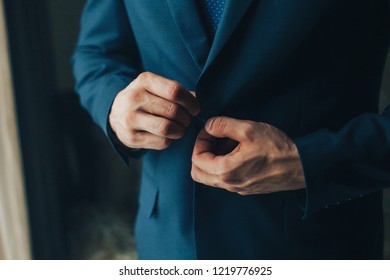 Buttoning a jacket hands close up. Stylish man in suit fastens buttons and straightens his jacket preparing to go out. Preparing for a wedding