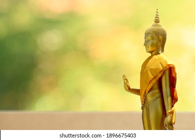 Buudha Head And Side Body Statue With Green And Yellow Bokeh Background As Golden Aura. Buddhism Pray For Faith And Asian Religion.