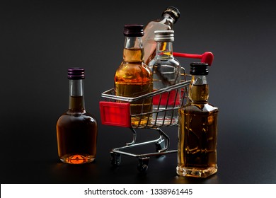 Buy Booze, Shopping The Liqueur Aisle And Purchase Of Alcoholic Beverages Concept Theme With Mini Bottles Of Alcohol In A Small Supermarket Cart Isolated On Black Background