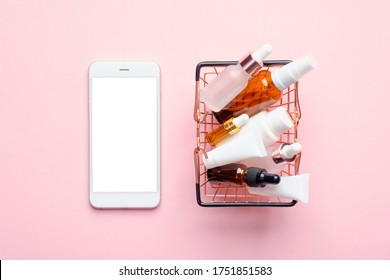 Buy Cosmetics Online Concept. Flat Lay Mobile Phone With Blank Screen Mockup And Shopping Basket Full Of Cosmetics Products On Pink Background. Flat Lay, Top View.