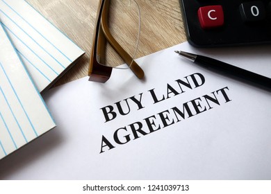 Buy land agreement form with pen, calculator and glasses in office