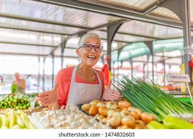 Buy Local At The Farmer's Market. Greengrocer Selling Organic Fresh Agricultural Product At Farmer Market. Female Stall Holder At Farmers Fresh Food Market