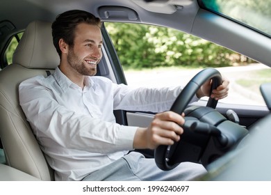 Buy New Car, Going To Office, Traffic In City, Covid-19 Quarantine And Social Distancing. Happy Millennial Guy Driver In White Shirt At Steering Wheel, Driving New Auto In Street, Inside, Free Space