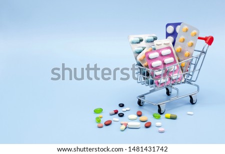 Buy and shopping medicine concept. Various capsules, tablets and medicine in shop trolley on a blue background. Creative idea for health care, health insurance and pharmaceutical company. Copy space.
