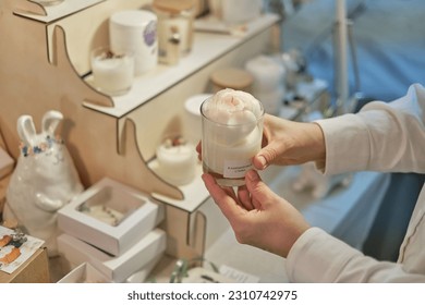 buyer acquires a distinctive, artistically designed candle from a devoted craftsman, set in a bustling market brimming with handcrafted candles and a diverse range of locally sourced products. - Shutterstock ID 2310742975