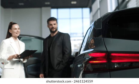 The buyer, a client of a modern car dealership, chooses a car. A dealer talks about a new model of a modern electric car. The concept of test drive, buying an electric car or renting it.
