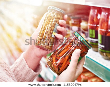 Buyer hands with a can of canned capers and hot red peppers in the store