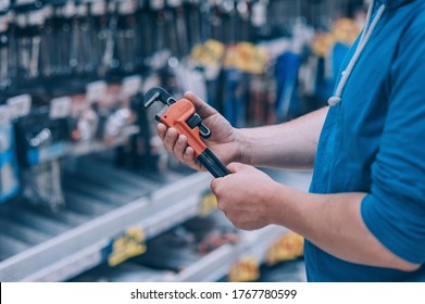 The buyer in the hardware store selects the goods. A man holds a wrench in his hand - Shutterstock ID 1767780599