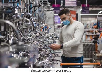 A Buyer Wearing Medical Mask Shopping For Bathroom Equipment In Hardware Store. Touching Faucet Crane Or Water Tap.