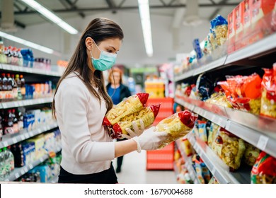 Buyer wearing a protective mask.Shopping during the pandemic quarantine.Nonperishable smart purchased household pantry groceries preparation.Woman buying few pasta packages.Budget pastas and noodles. - Powered by Shutterstock