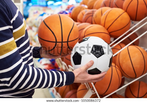 Buyer\'s hands with football and basketball in the\
sports shop