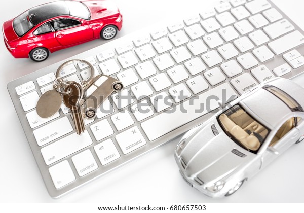 Buying car online. Car keys and toy car on\
keyboard on white background top\
view