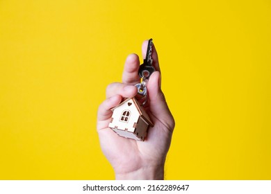 Buying A House. The Buyer Receives The Key To The Property. Mortgage Apartment. Keys And A Small Wooden House In Hand. Handing Over The Keys To The Owner.