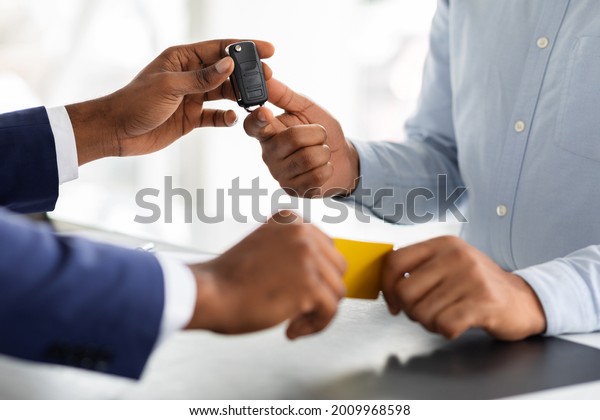 Buying\
Or Renting Vehicle. Man Giving Credit Card To Manager And Taking\
Car Keys, Unrecognizable African American Customer Standing At Desk\
In Dealership Office, Cropped Image, Closeup\
Shot