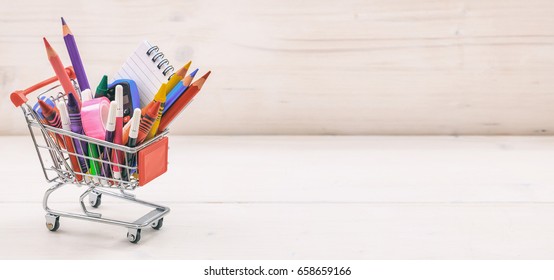 Buying School Supplies. Stationery For Kids In A Shopping Cart On White Wooden Background, Copy Space