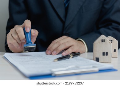 Buying And Selling Real Estate Or Borrowing Money, Bank Loans, Approved Investments.Businessman Rubber Stamp Document On Desk.