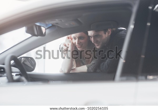 Buying their first car together. High\
angle view of young car salesman standing at the dealership telling\
about the features of the car to the\
customers.