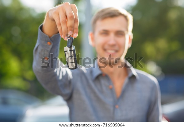 Buying used car. Car Dealer Inventory. Used\
cars store. Male wants to buy the car. Close-up of hand with a\
wrist watch, holding key from auto, finance for car concept. Happy\
life. Blurred\
background.
